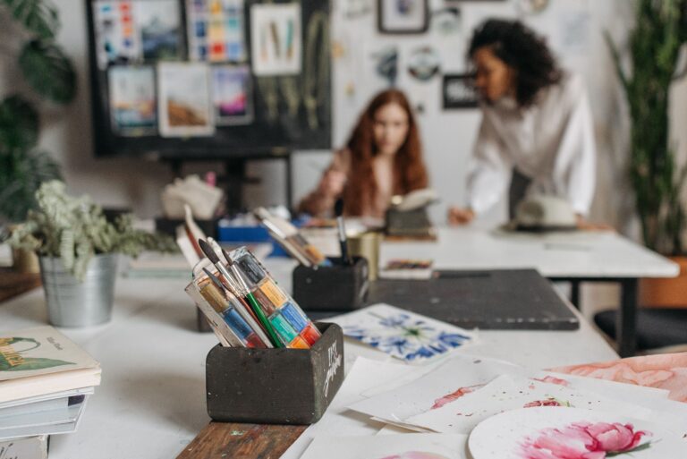 Academics Art studio workspace with paint brushes and artists creating in the background.